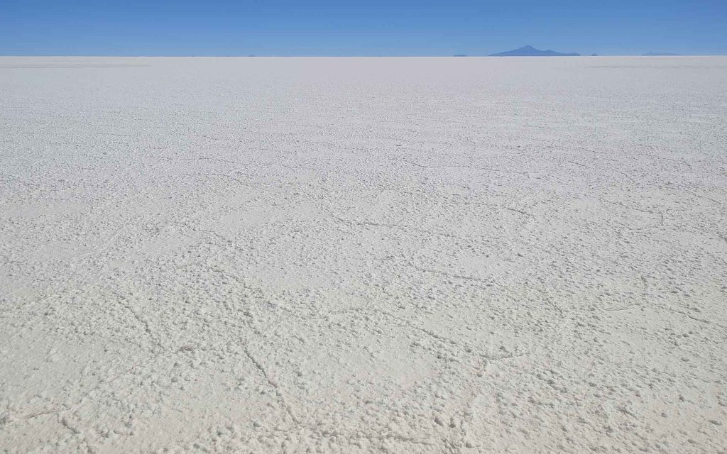Hexagonal cracks from evaporation on Uyuni salt flat; Tunupa Volcano at the bottom.