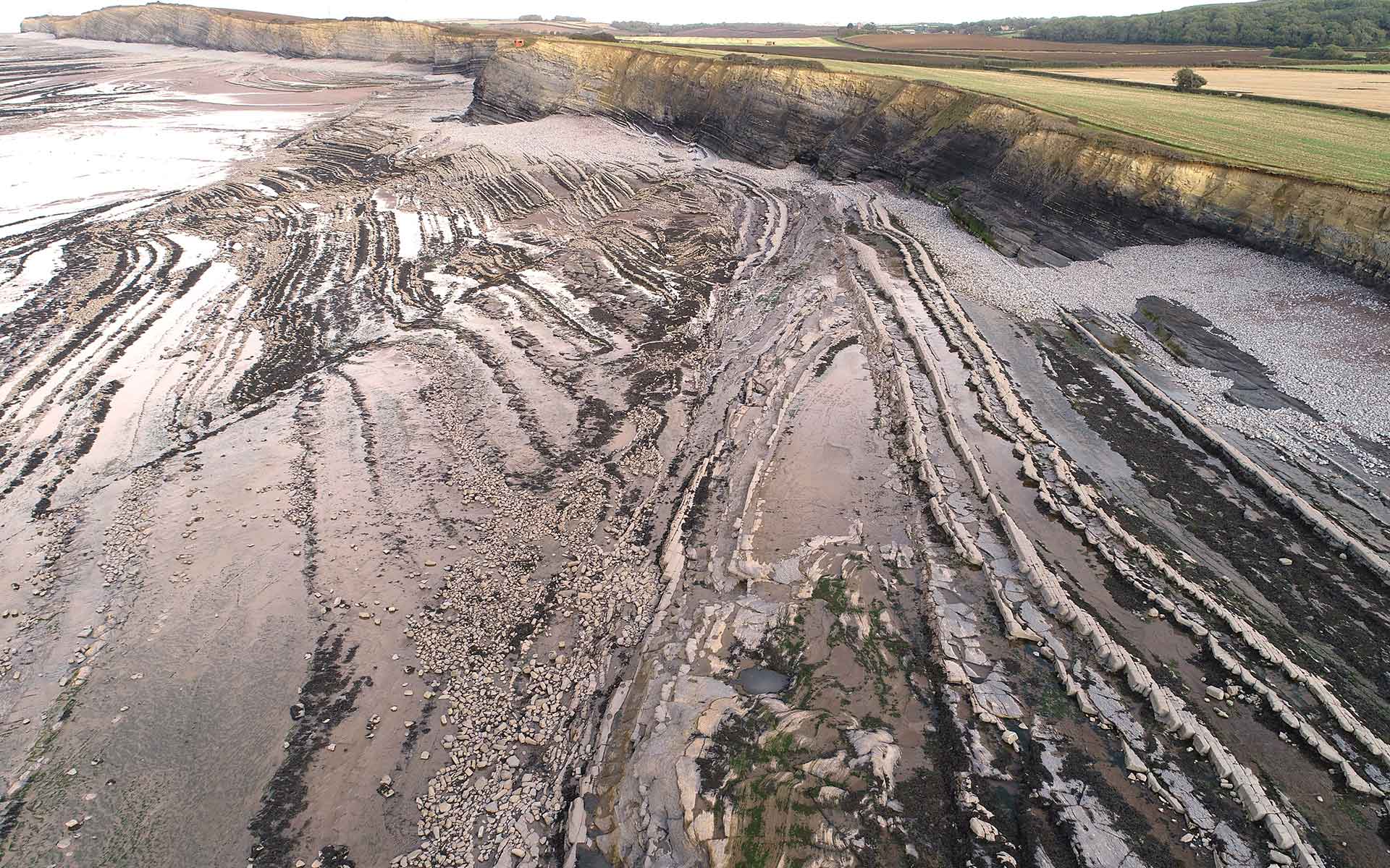 Photograph taken from a drone looking eastwards from Kilve, showing normal faults and folds exposed on the beach and cliffs.